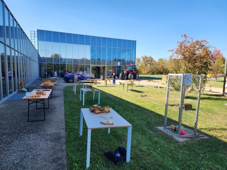 Tavoli con rompicapo e giochi in legno allestiti sul prato accanto alla sede MTA